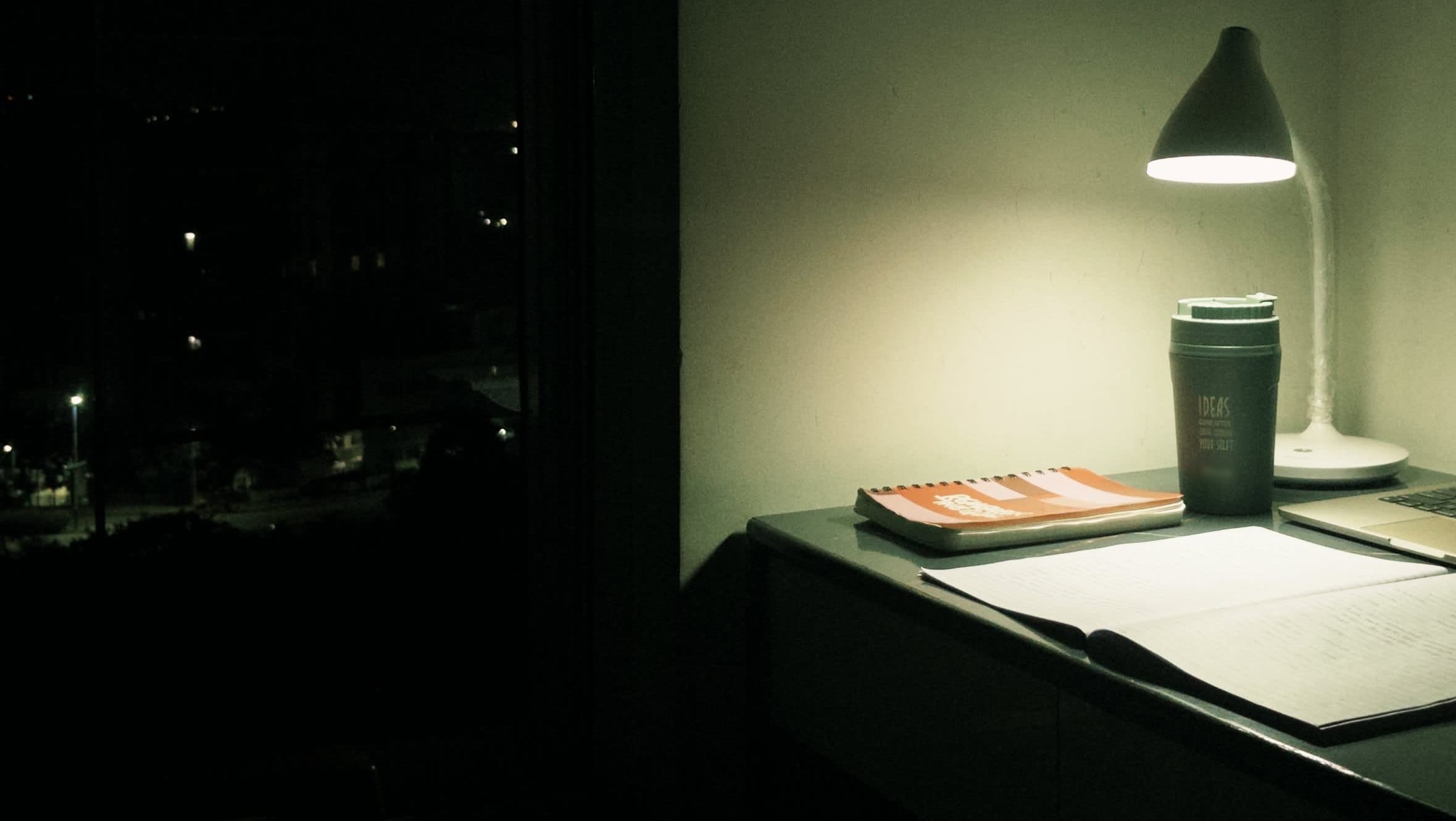 Desk lamp over papers in a dark room