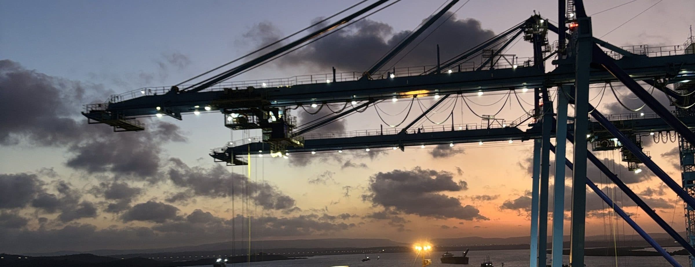 Port crane over a container ship at dusk
